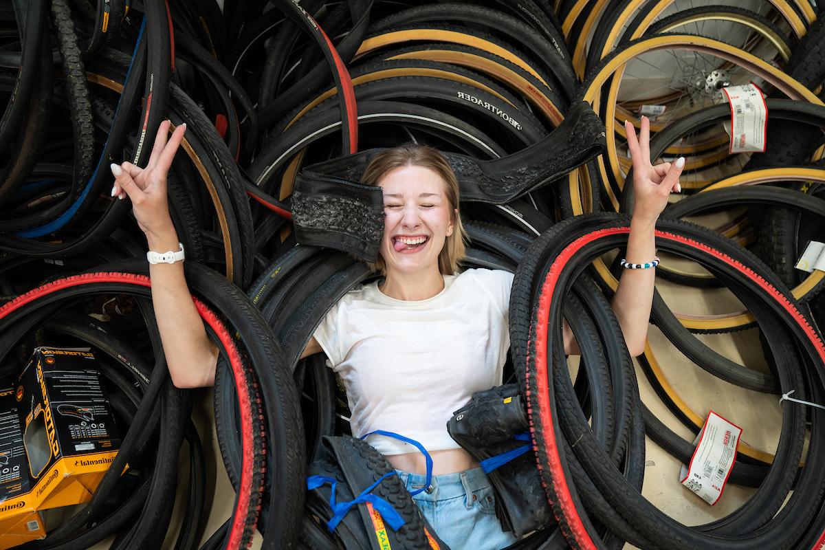 阿拉贝拉·卡明斯微笑着在一堆自行车轮子上举着和平标志