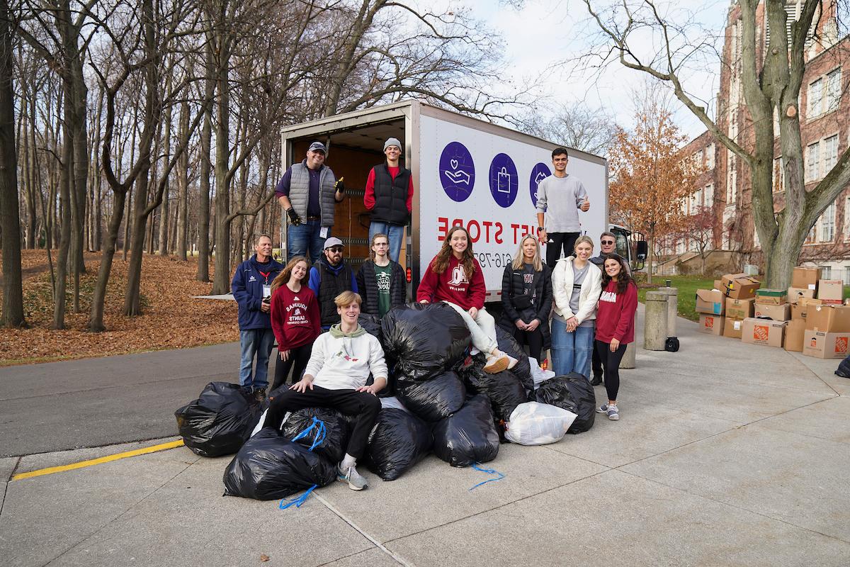 几个学生站在一堆装满梅尔·特罗特捐款的垃圾袋和一辆梅尔·特罗特卡车旁